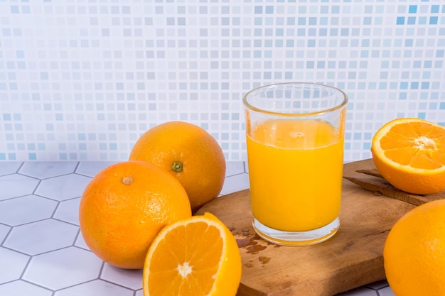 Foto glas sinaasappelsap geperst over een plank en sinaasappels eromheen