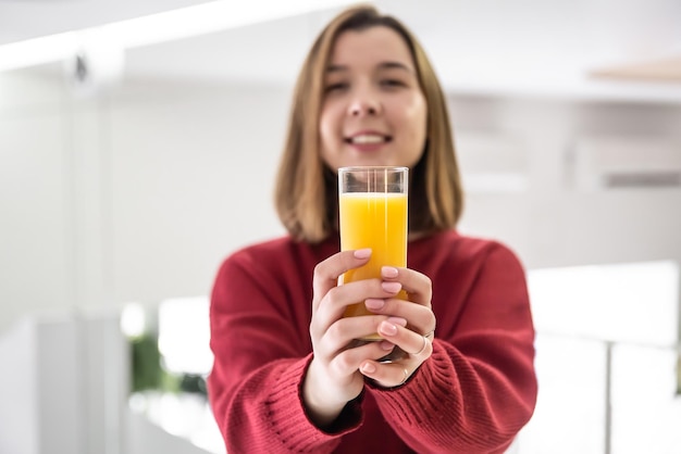 Glas sinaasappelsap in de handen van een gelukkige jonge vrouw wazige achtergrond