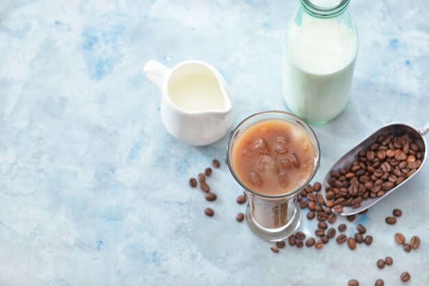 Glas smakelijke ijskoffie met melk op kleurenmuur