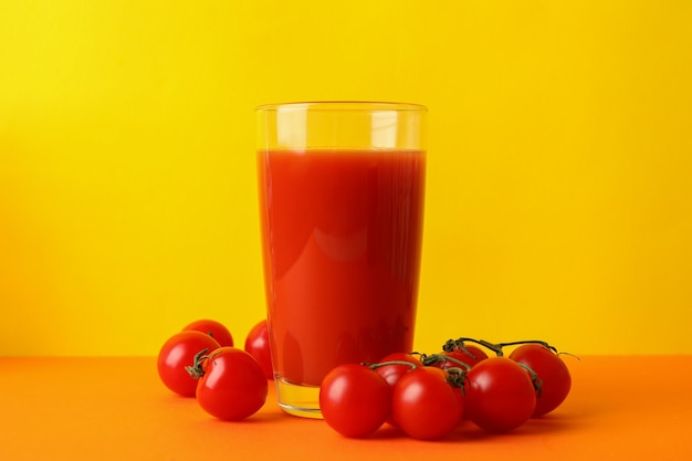 Glas tomatensap en tomaten tegen gele achtergrond