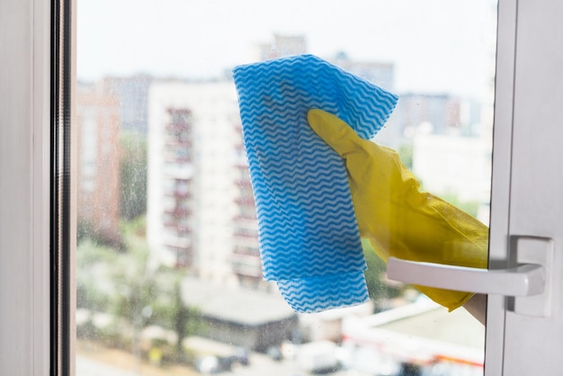 Glas van huisraam schoonmaken door blauwe doek