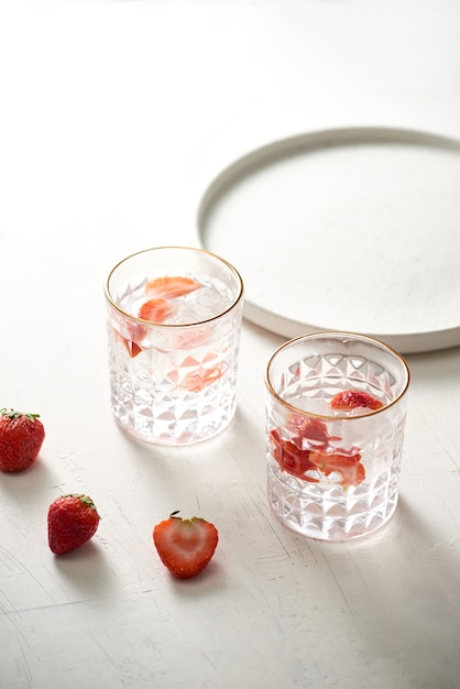 Glas vers, koud doordrenkt water met verse aardbeien en verse aardbeien ernaast