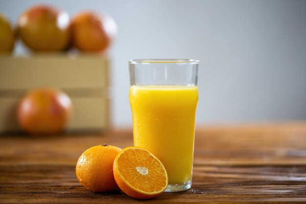 Glas vers sinaasappelsap op houten lijst met grapefruits op achtergrond