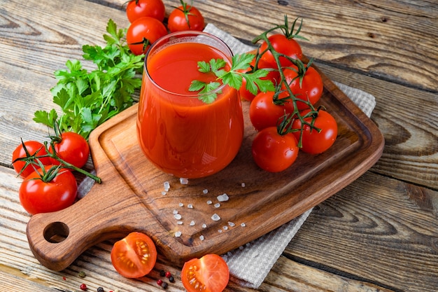 Glas vers tomatensap en tomaten op de houten achtergrond. Hoge kwaliteit foto