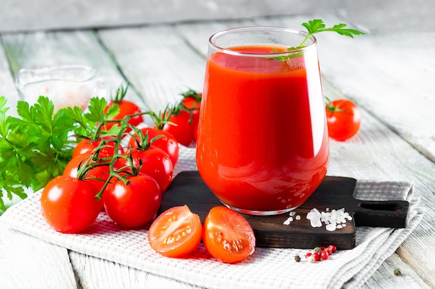 Glas vers tomatensap met tomaten close-up op tafel.