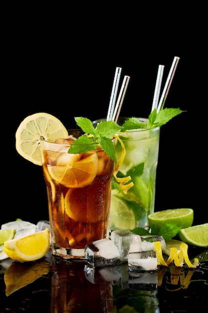 Glas verse long island ice tea en mojito cocktail studio opname op zwarte achtergrond