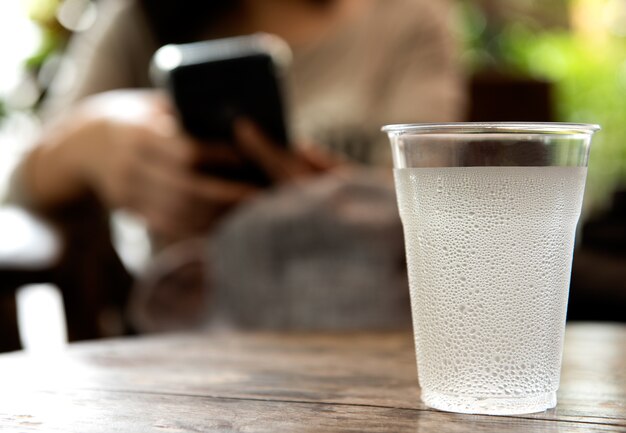 Glas water met druppel water op de houten tafel.