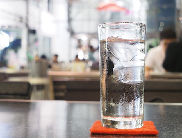 Glas water met ijs op de lijst in restaurant bij nacht