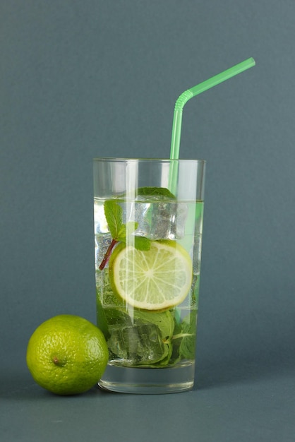 Glas water met ijsmunt en limoen op grijze achtergrond