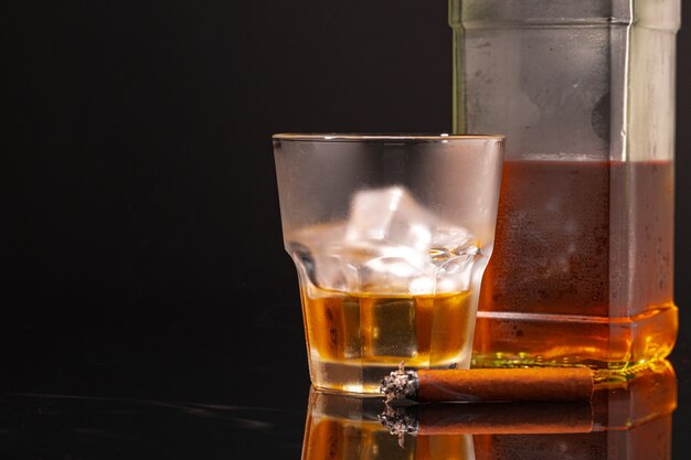 Foto glas whisky en brandende sigaar op zwarte achtergrond close-up