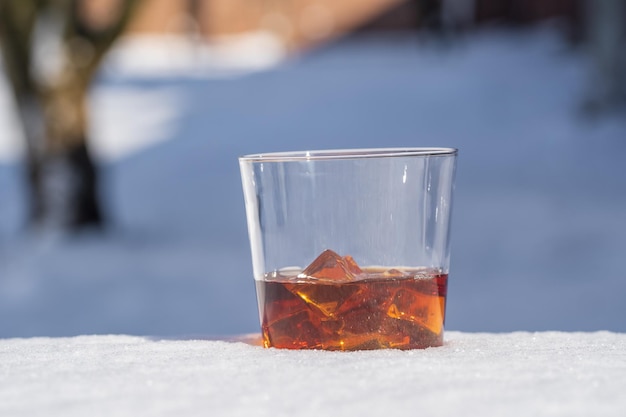 Glas whisky met ijs op een bedje van sneeuw en witte achtergrond close-up