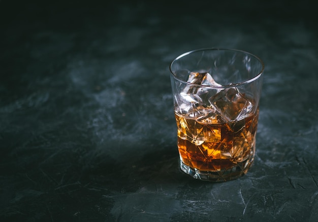 Foto glas whisky met ijs op een donkere tafel alcoholische drank klaar om te drinken