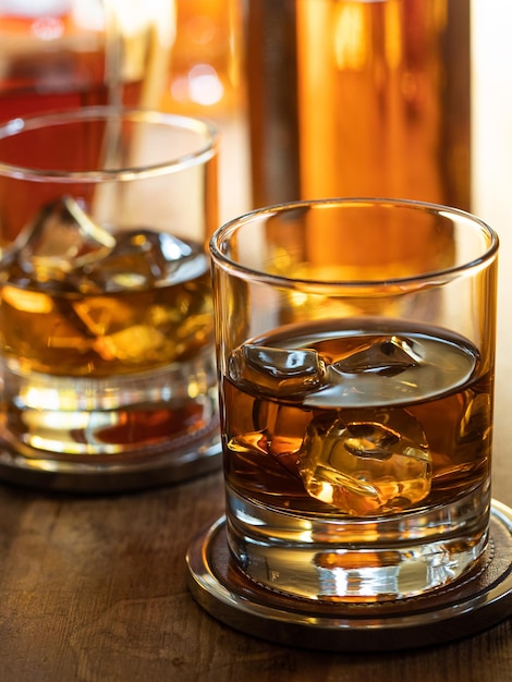 Glas whisky on the rocks op een houten barblad