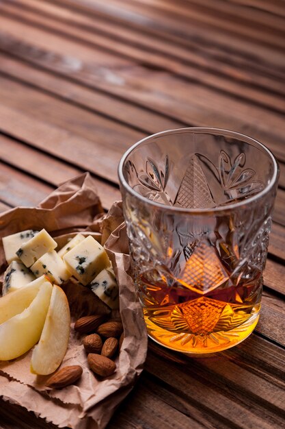 Glas whisky op een houten tafel met een snack