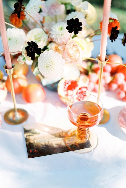 Glas wijn staat op tafel naast een boeket bloemen en kaarsen