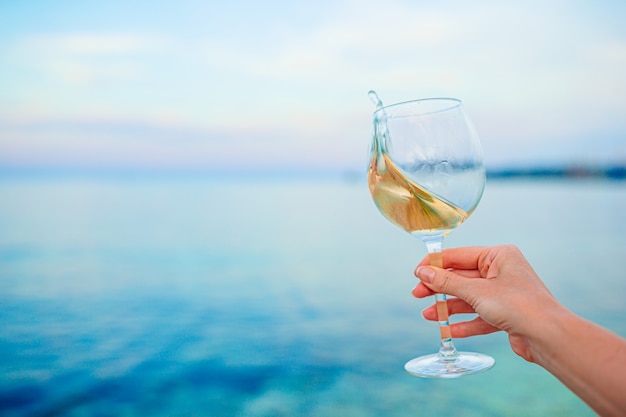 Glas witte wijn op tropisch strand op de zonsondergang