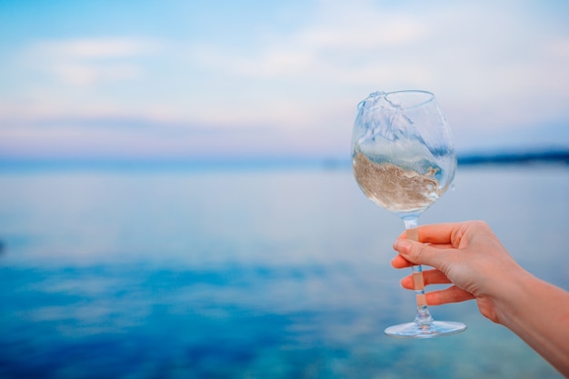 Glas witte wijn op tropisch strand op de zonsondergang