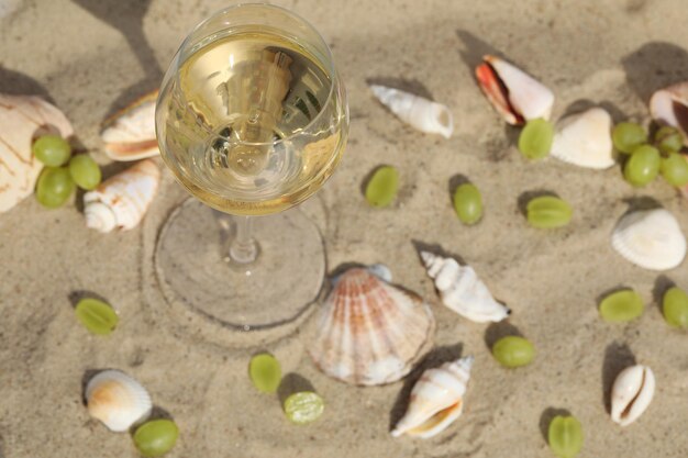 glas witte wijn op zand als achtergrond met schelpen