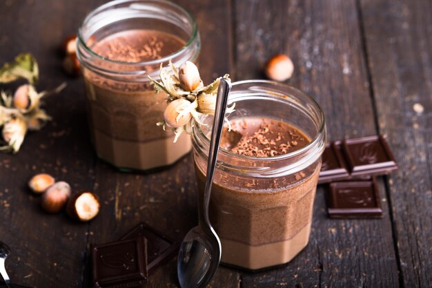 Glas zelfgemaakte yoghurt met chocolademousse en chocolade snoep en lepel