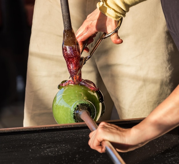 Glasblazer werkt op sierlijke groene fles