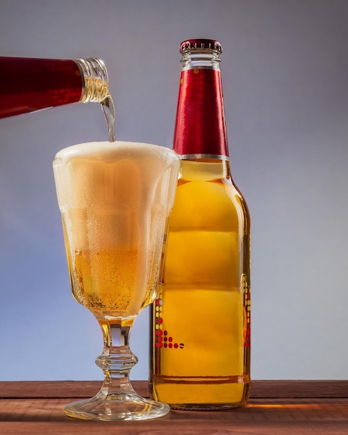 Glasfles en glas met gegoten schuimbier op een blauwachtig achtergrond verticaal frame