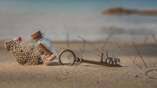 Glasfles en sleutel op zee strand