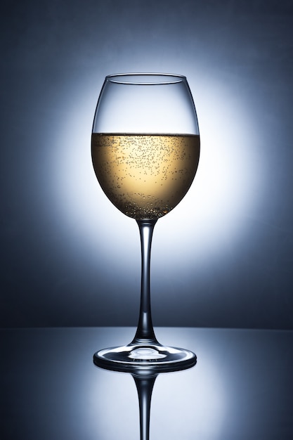 Glasglas met champagne en bubbels op tafel.
