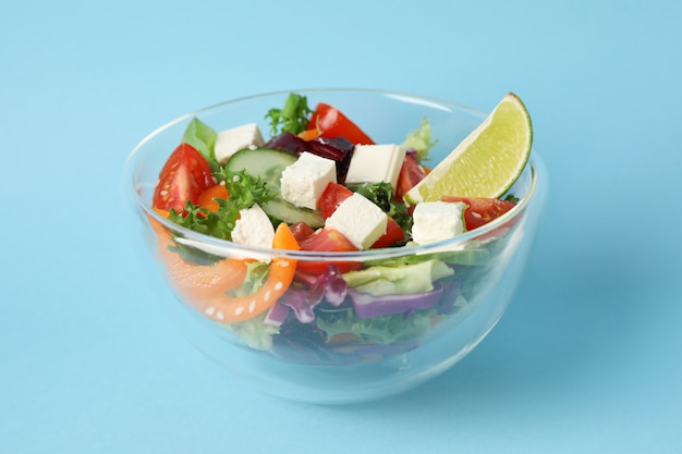 Glaskom met verse salade op blauw