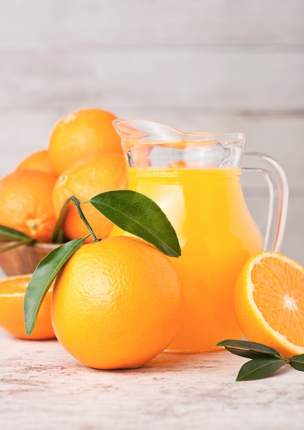 Glaskruik organisch vers jus d'orange met ruwe sinaasappelen op lichte houten achtergrond