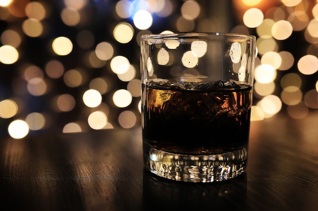 Glass of alcohol with ice on blured background with circle bokeh