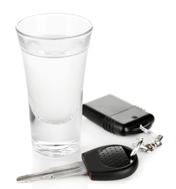 Glass of alcoholic drink and car key isolated on white