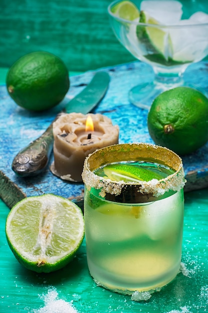 Glass alcoholic drink and lime fruits on wooden texture.