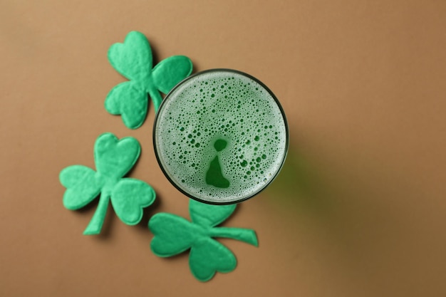 Bicchiere di birra e foglie di trifoglio su sfondo beige