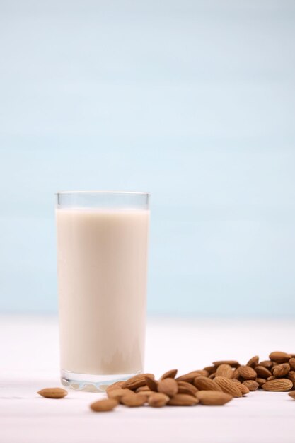 Glass of almond milk with almond nuts on white wooden table Dairy alternative milk for detox healthy eating and diets