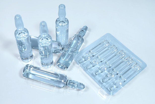 glass ampoules with a transparent drug for injection on light blue background