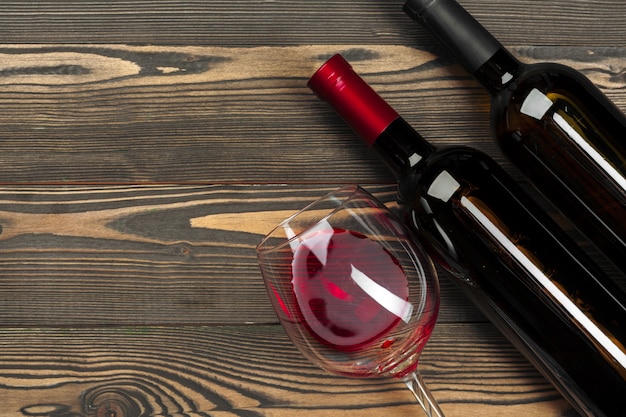 写真 ガラスと木製の背景、トップビューで赤ワインの瓶