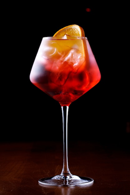 glass of aperol spritz cocktail on a black