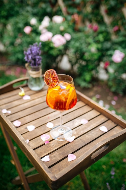 Glass of aperole spritz cocktail garnished with orange slice on the wodoen tray