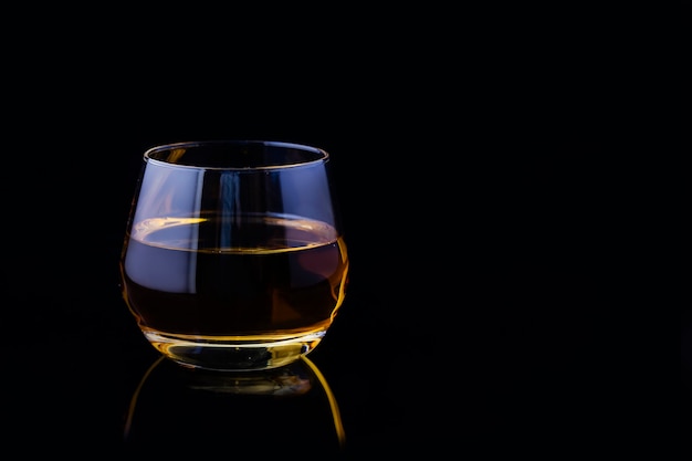 A glass of apple juice on a black background.