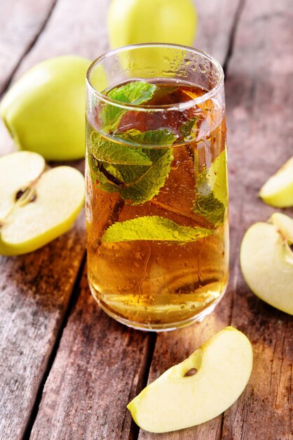 Glass of apple juice with fruits and fresh mint on table close up