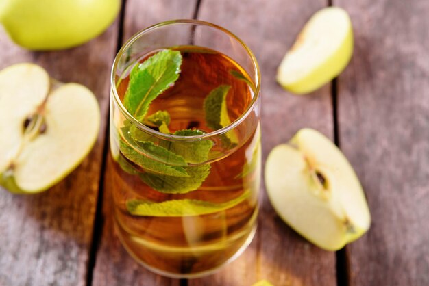 Glass of apple juice with fruits and fresh mint on table close up