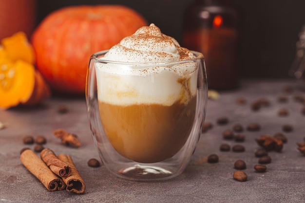 秋のカボチャ ラテ ホイップ クリームとスパイスのグラス 暗い背景にカボチャとシナモンのコーヒー