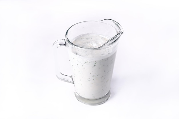 Стакан айрана с укропом и петрушкой, выделенный на белом изолированном фоне. Холодный йогуртовый напиток.