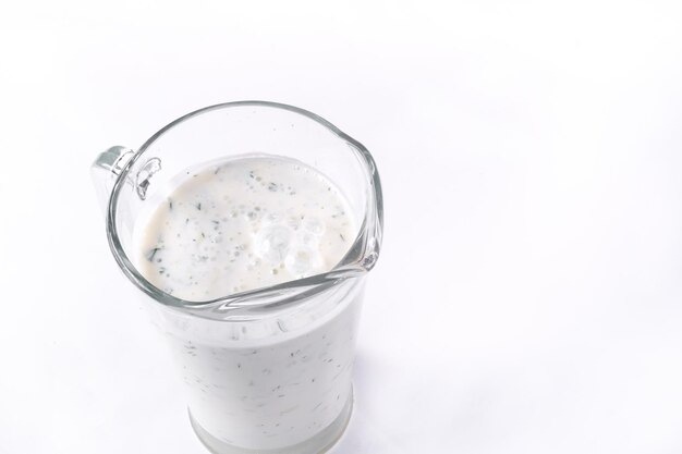 A glass of ayran with dill and parsley, highlighted on a white isolated background. Cold yogurt drink.