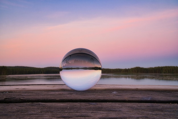 Стеклянный шар на деревянном пирсе у шведского озера в вечерний час Природа Скандинавия