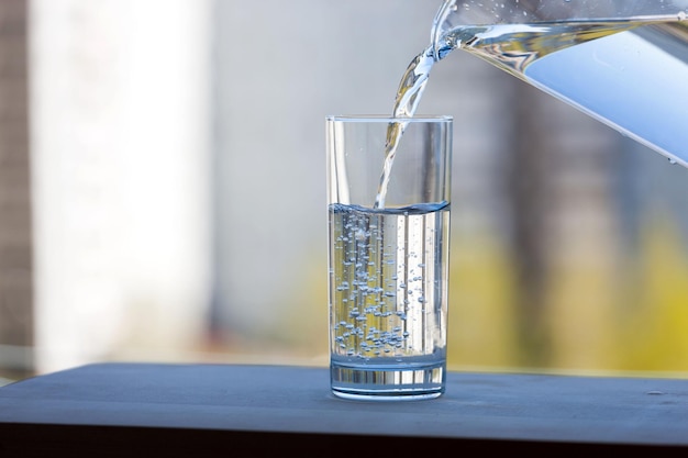 Photo the glass beaker is filled with drinking water on open air summer sunny day