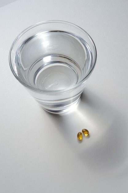A glass beaker and two yellow tablets with vitamins. close-up.