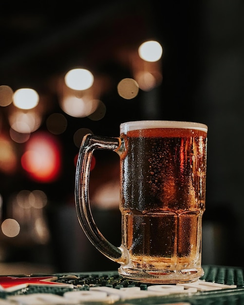 A glass of beer on a bar with the word beer on it