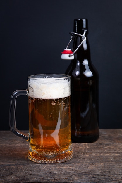 Glass of beer and beer bottle on a black