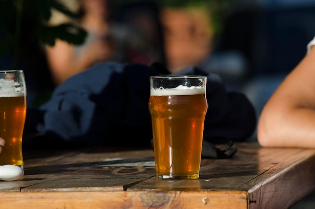 glass of beer on a beer patio table with a person waiting to drink it pint of beer